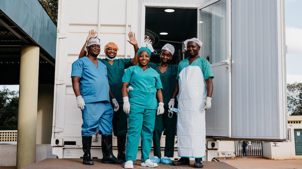 Surgical staff outside a mobile clinic, following successful surgery.