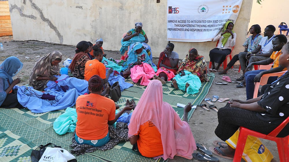 Women and girls gathered, knitting and making, bedsheet weaving, at Hope Restoration South Sudan GBV response site- Renk